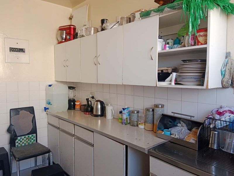 A functional kitchen area featuring white cabinetry, laminate countertops, and a tiled backsplash, offering a practical layout for daily food preparation.