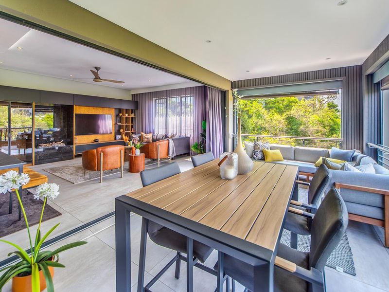 Spacious open-plan living and dining area featuring large sliding glass doors that open onto a balcony, with modern built-in cabinetry and tiled flooring.