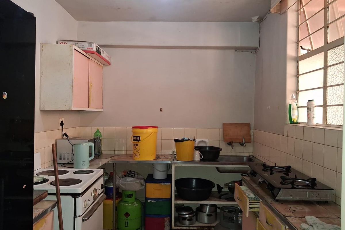 A dated kitchen featuring basic cabinetry, tiled backsplash, and integrated cooking appliances, requiring modernization to improve functionality and aesthetic appeal.