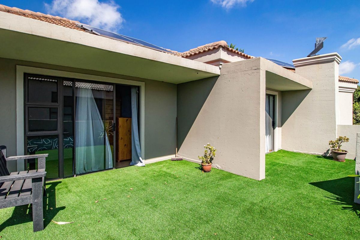 A private rear patio area featuring artificial turf, covered outdoor space, and direct access to the interior through sliding glass doors.