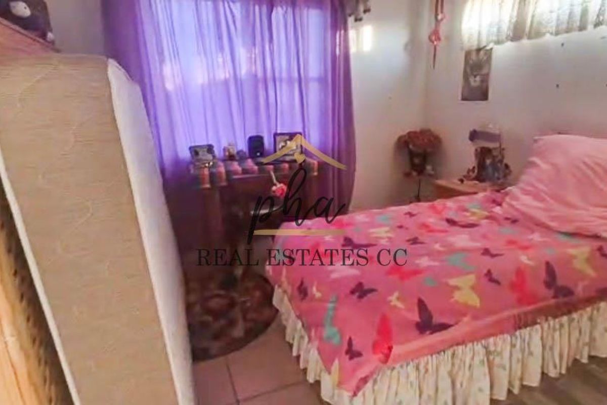 A bedroom featuring tiled flooring and a window with curtains.