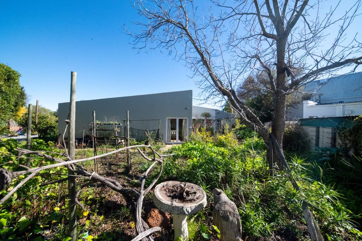 A view of the rear exterior of the house featuring a modern concrete facade and glass sliding doors overlooking a garden area.