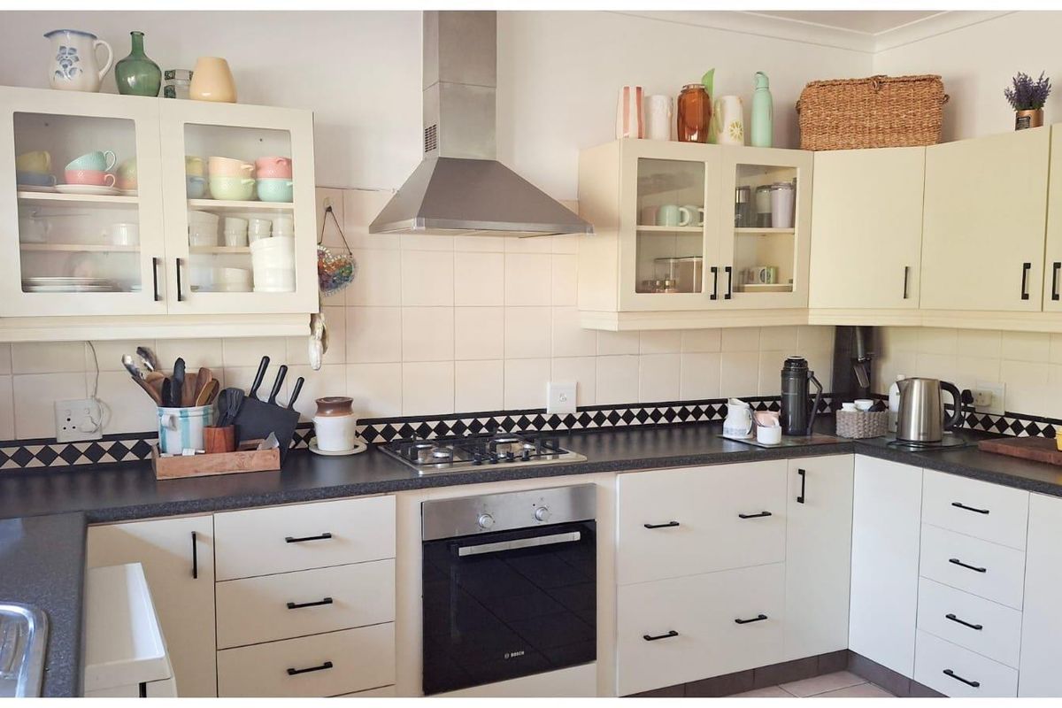 A functional kitchen featuring cream cabinetry, dark laminate countertops, a gas hob, built-in oven, and a stainless steel extractor fan.