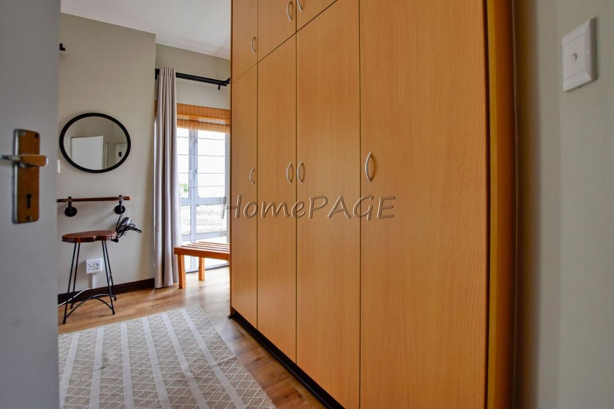 A bedroom featuring built-in wooden cabinetry, laminate flooring, and a window with natural light.