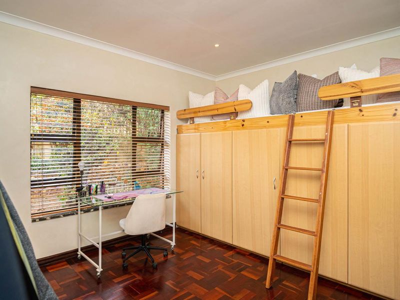 Bedroom featuring extensive built-in cabinetry with an integrated loft bed, wooden ladder, parquet flooring, and large window with venetian blinds.