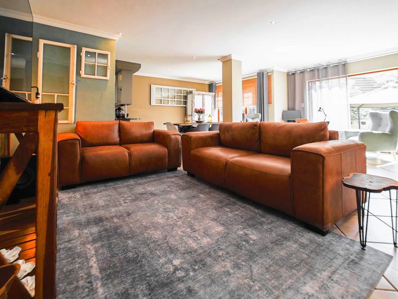 Spacious open-plan living area featuring tiled flooring, recessed downlighting, and large sliding glass doors providing access to the outdoor patio space.