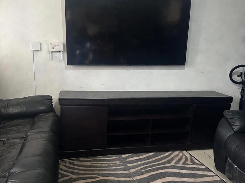 A living room area featuring tiled flooring and wall-mounted electrical points, currently showing signs of wear on the wall surfaces.