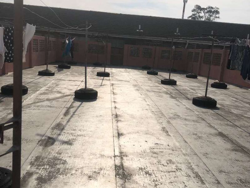 A large, open-air concrete utility terrace featuring perimeter boundary walls with ventilation blocks, currently utilized as a drying area.