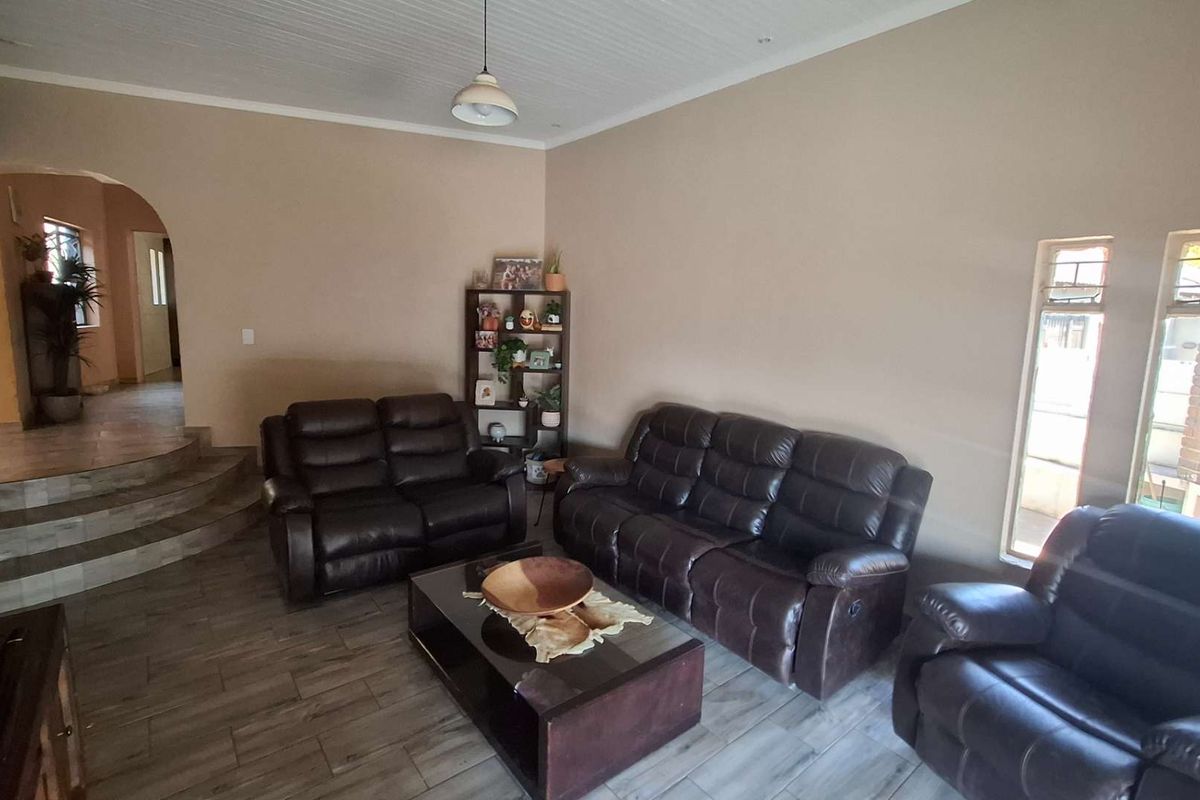 Spacious living room featuring tiled flooring, a beadboard ceiling, and an arched entryway leading to an elevated transition area.
