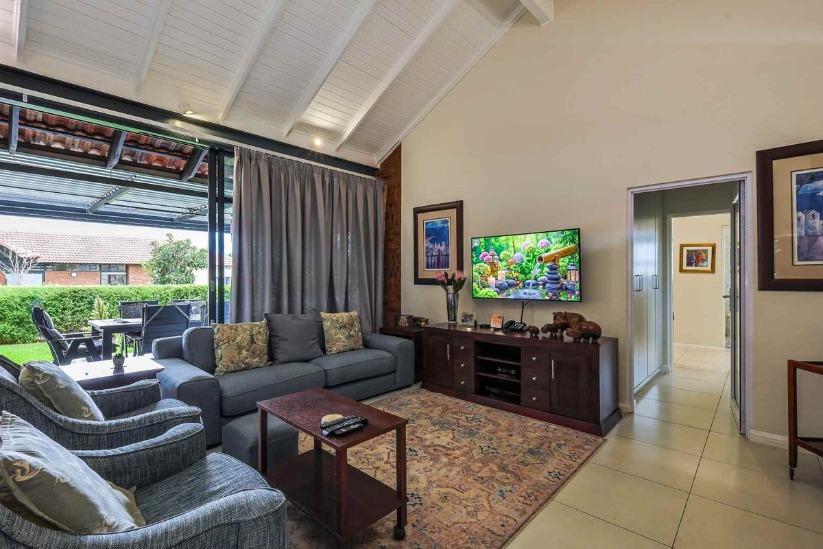 Spacious living area featuring high vaulted ceilings, tiled flooring, and large sliding glass doors providing seamless access to the covered outdoor patio.