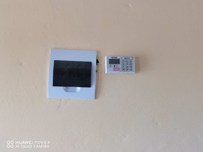 A utility wall featuring a mounted electrical distribution board and a security alarm system keypad.