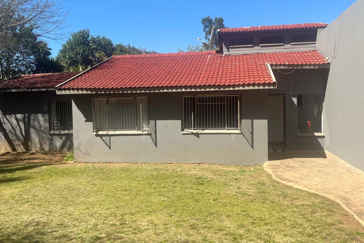 Rear view of the house featuring a terracotta tiled roof, security bars on windows, and a paved walkway leading to the entrance.