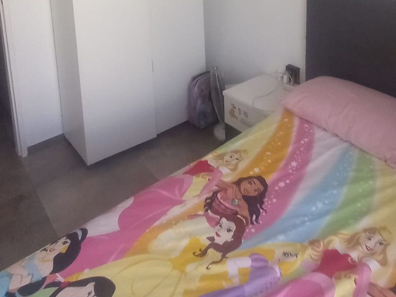 A bedroom featuring a built-in wardrobe and tiled flooring, offering a functional space for rest.