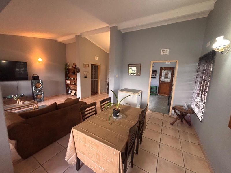Open-plan living and dining area featuring tiled flooring, high ceilings, and direct access to adjacent rooms.