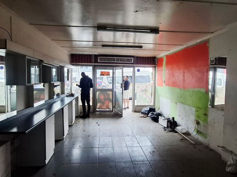 Vacant commercial space featuring tiled flooring, built-in cabinetry, and an air conditioning unit, requiring cosmetic refurbishment and wall repairs.