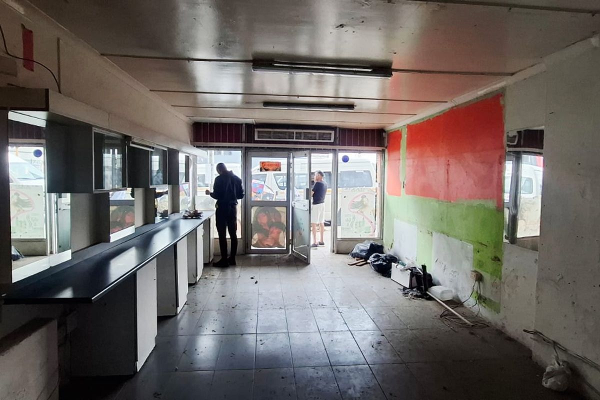 Vacant commercial space featuring tiled flooring, built-in cabinetry, and an air conditioning unit, requiring cosmetic refurbishment and wall repairs.