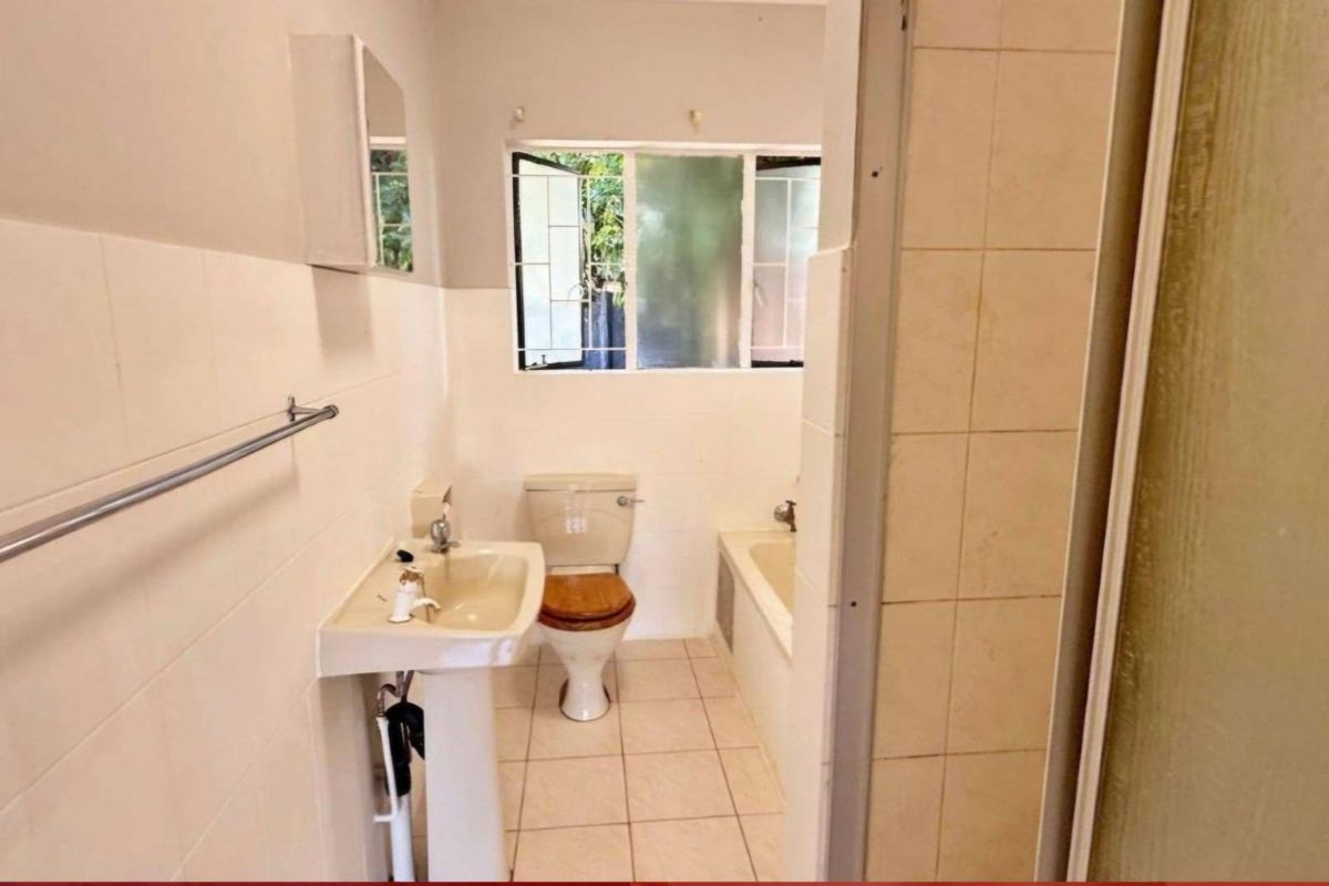 A dated bathroom featuring a pedestal basin, toilet, and built-in bathtub with tiled walls and flooring.
