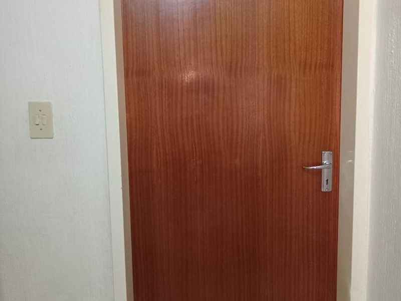 A standard interior wooden door with a transom window above, located in a hallway area.