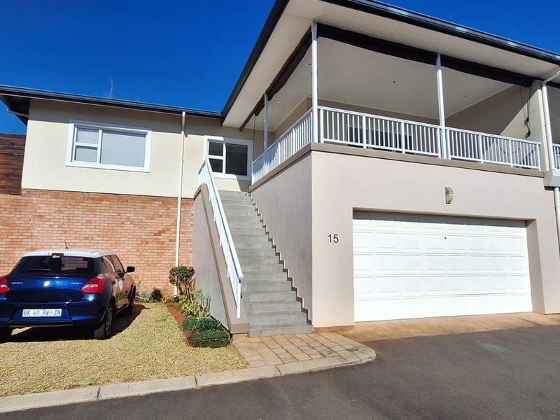 Front elevation of a townhouse featuring a double garage, an elevated balcony, and an external staircase leading to the main entrance.