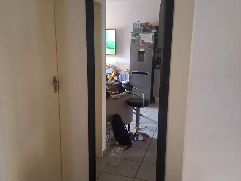 A hallway featuring a full-length wall mirror and tiled flooring, providing a view into the adjacent living and kitchen area.