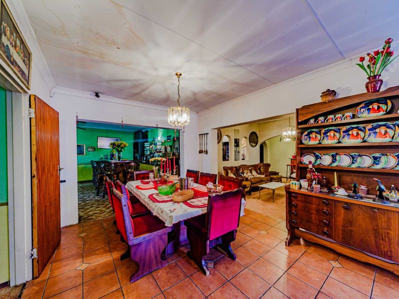 Dining room featuring tiled flooring and an open-plan layout connecting to adjacent living spaces, showing visible signs of ceiling water damage.