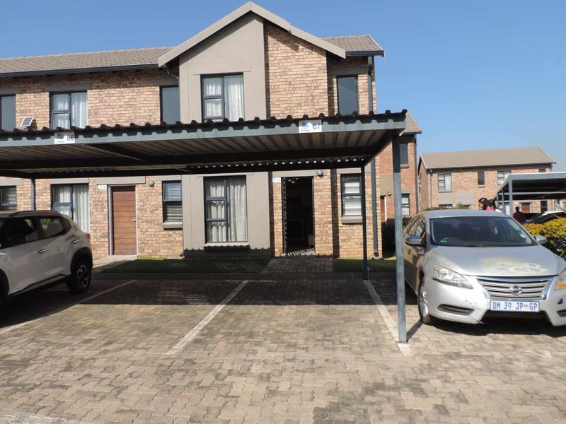 Front elevation of a double-storey townhouse featuring a brick facade, tiled roof, and a dedicated covered carport parking area.