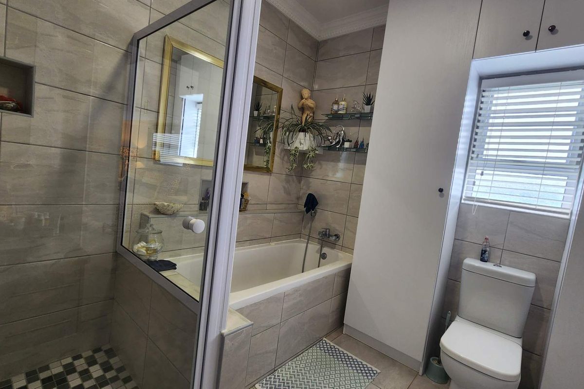 Modern bathroom featuring a built-in bathtub, separate glass-enclosed shower, built-in storage cabinetry, and neutral floor-to-ceiling tiling.