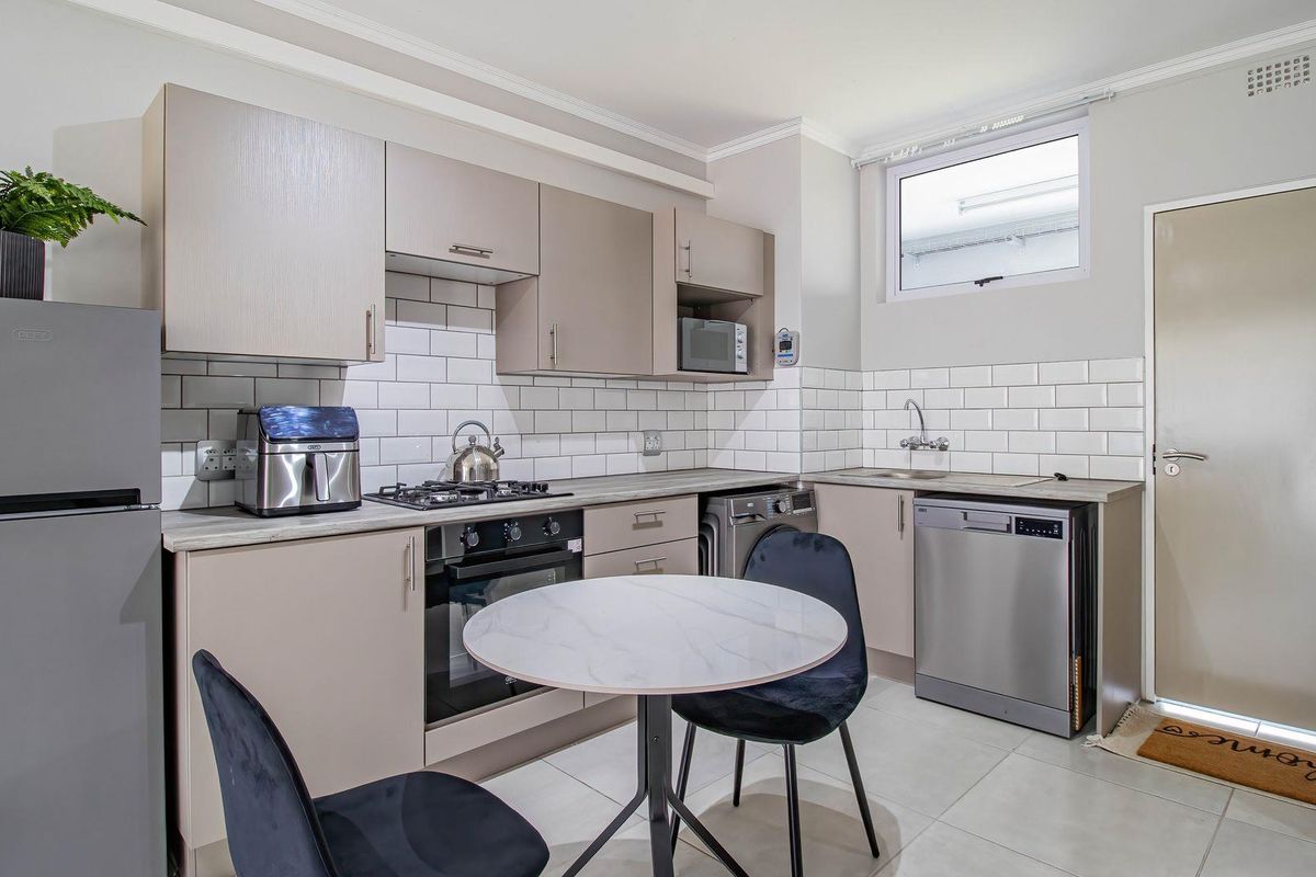 Modern kitchen featuring neutral cabinetry, subway tile backsplash, gas hob, built-in oven, and integrated appliance spaces with tiled flooring.