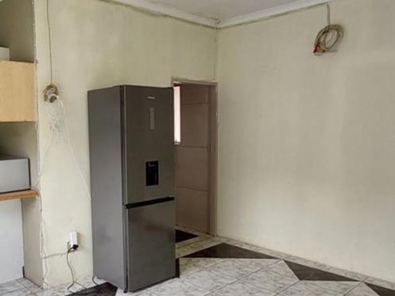 A sparse kitchen area featuring tiled flooring and exposed electrical wiring, requiring cosmetic updates and finishing to improve the overall aesthetic.