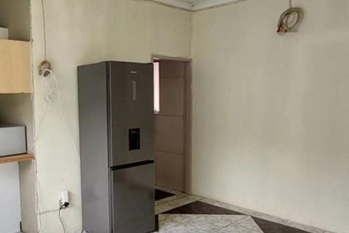 A sparse kitchen area featuring tiled flooring and exposed electrical wiring, requiring cosmetic updates and finishing to improve the overall aesthetic.