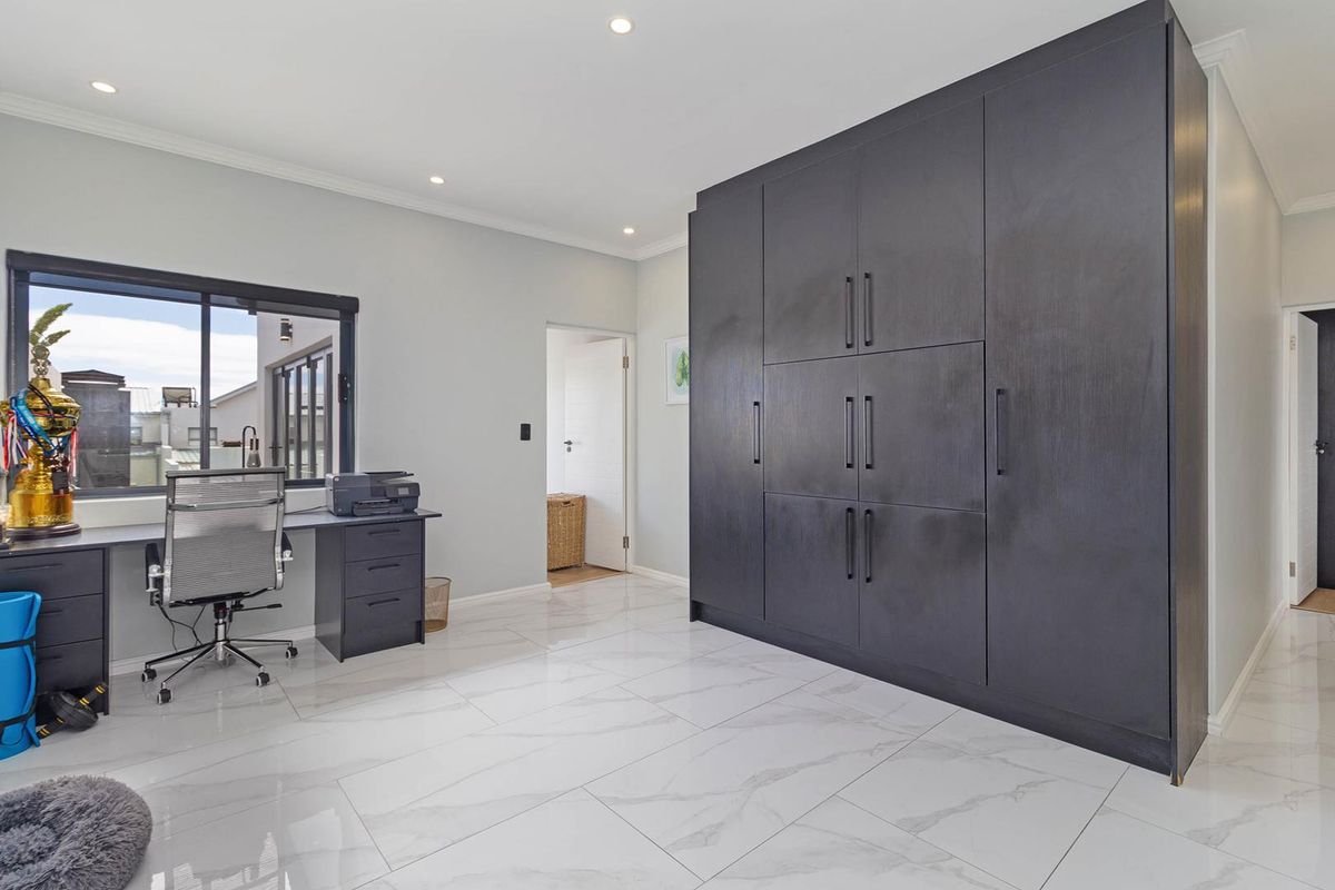 A modern bedroom or office space featuring large dark built-in cabinetry, polished marble-look floor tiles, and recessed ceiling lighting.