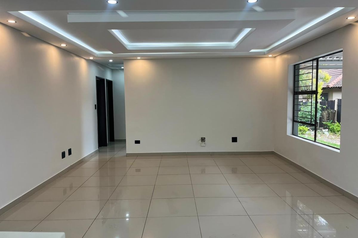 Spacious living area featuring modern recessed tray ceiling with integrated LED lighting and large polished floor tiles.
