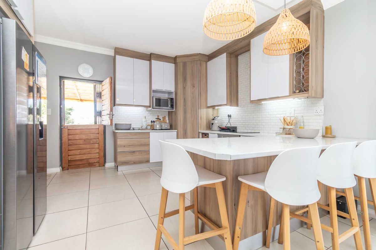 Modern kitchen featuring a central island with breakfast bar, white subway tile backsplash, built-in cabinetry, and direct access to an outdoor area.