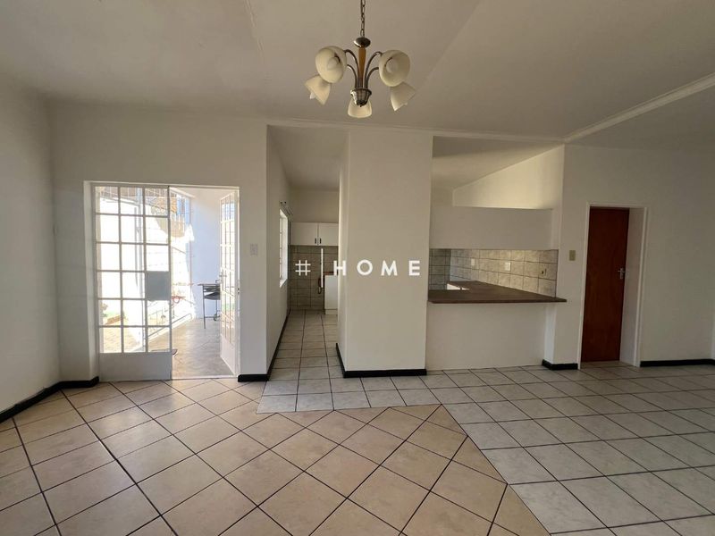Open plan living area featuring tiled flooring, a kitchen breakfast bar, and direct access to an outdoor patio area.