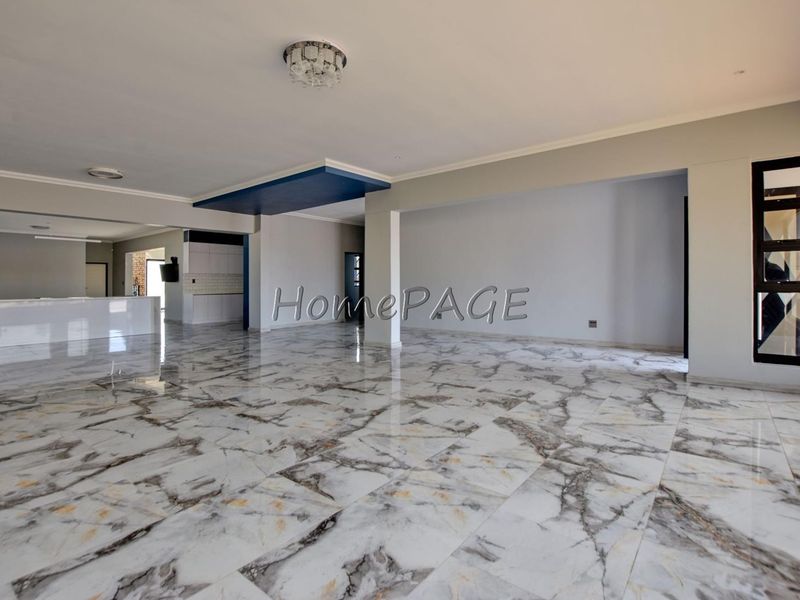 Spacious open-plan living and kitchen area featuring high-gloss marble-look floor tiles and a modern recessed ceiling design.