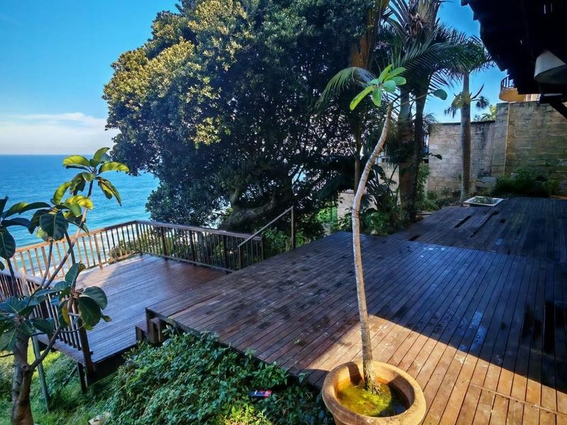 Spacious multi-level timber deck offering expansive ocean views, featuring a wooden balustrade and direct access to the surrounding garden area.