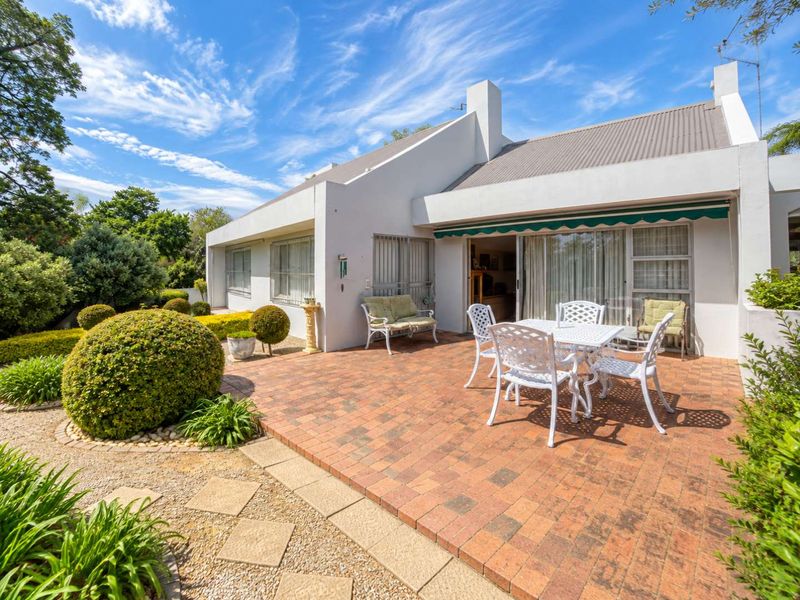A well-maintained rear patio featuring brick paving, a retractable awning, and direct access to the interior through sliding glass doors.