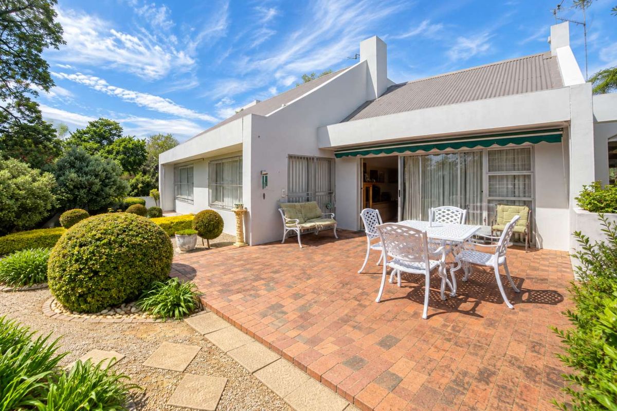 A well-maintained rear patio featuring brick paving, a retractable awning, and direct access to the interior through sliding glass doors.