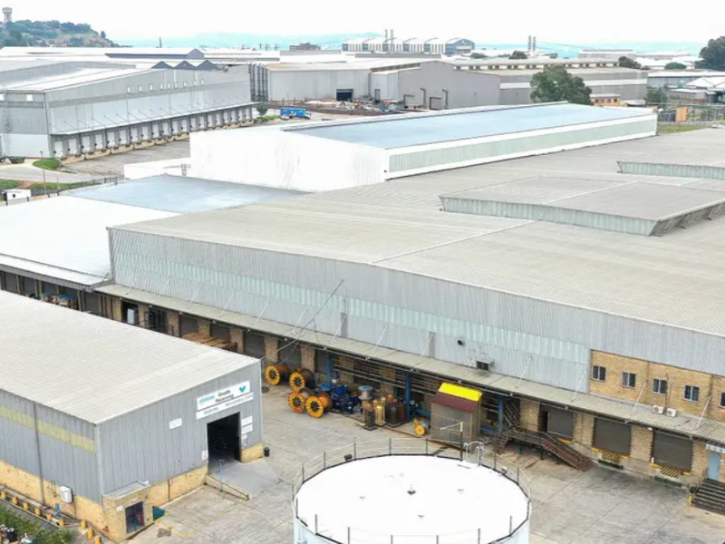 Aerial view of a large industrial warehouse complex featuring extensive metal roofing, multiple loading bays, and a secure perimeter yard area.