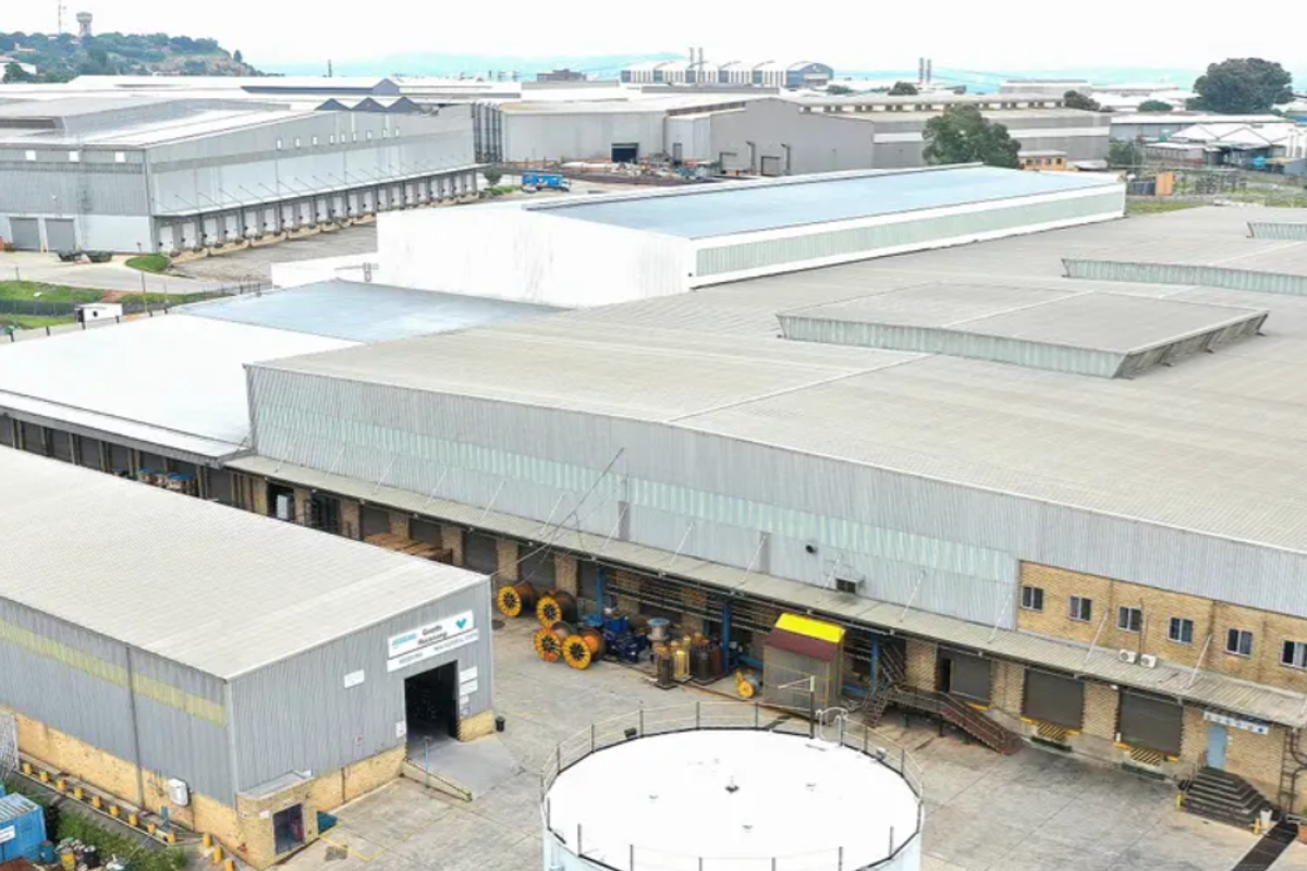 Aerial view of a large industrial warehouse complex featuring extensive metal roofing, multiple loading bays, and a secure perimeter yard area.
