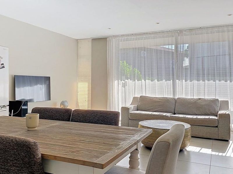 Bright open-plan living and dining area featuring neutral tiled flooring, recessed lighting, and large sliding glass doors providing ample natural light.