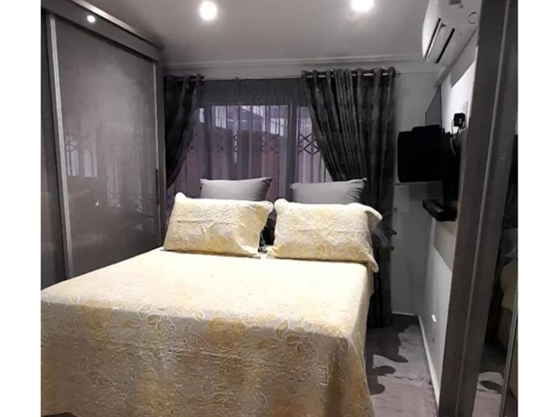 A well-maintained bedroom featuring built-in cupboards, recessed downlighting, and a wall-mounted split-system air conditioner.