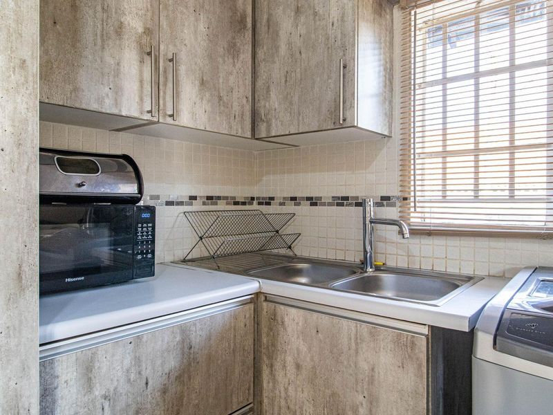 Compact scullery area featuring built-in cabinetry, a double stainless steel sink, and dedicated space for laundry appliances.