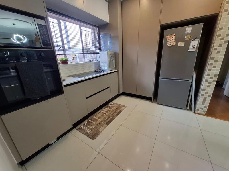 Modern kitchen featuring sleek built-in cabinetry, integrated oven and microwave, hob, subway tile backsplash, and polished tiled flooring.