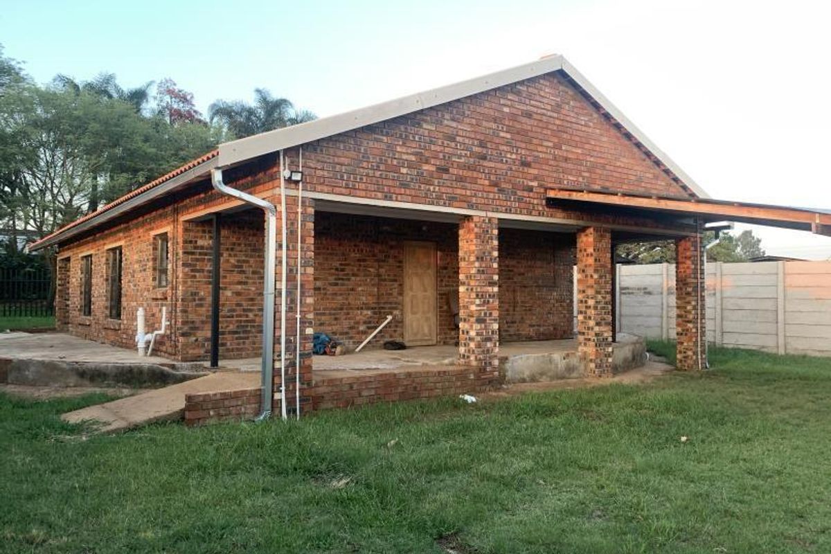 Rear view of a face brick farm dwelling featuring a covered patio area, concrete apron, and precast boundary walling.
