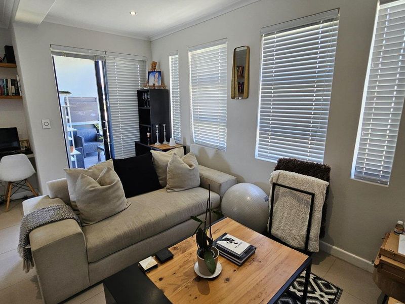 A bright and well-maintained living room featuring tiled flooring, recessed lighting, and sliding glass doors leading to an outdoor area.