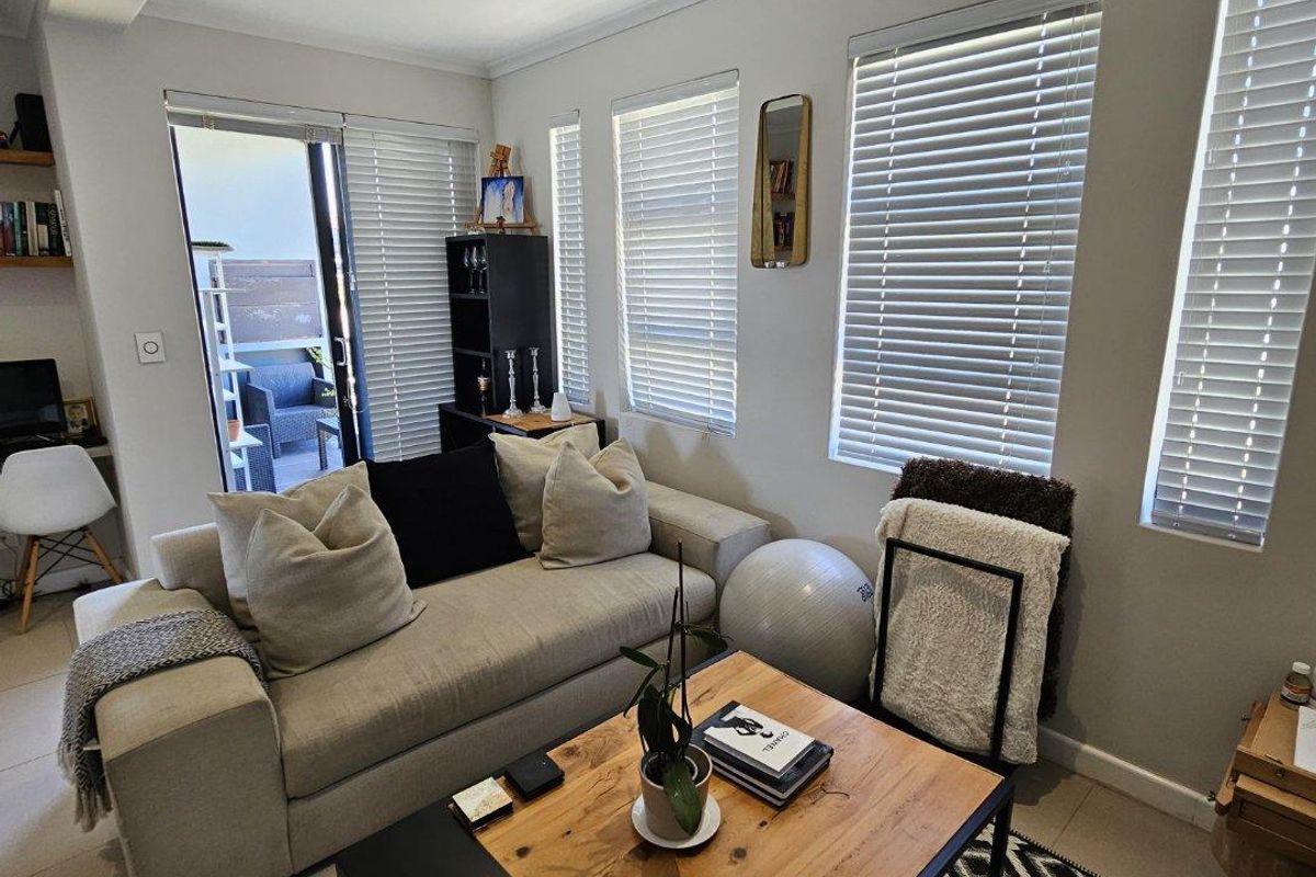 A bright and well-maintained living room featuring tiled flooring, recessed lighting, and sliding glass doors leading to an outdoor area.