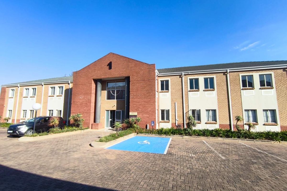 Front exterior view of a two-story brick office building featuring a prominent entrance, paved parking area, and designated accessible parking.