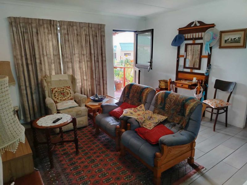 A living room area featuring tiled flooring and direct access to an outdoor space through a glass-paneled door.