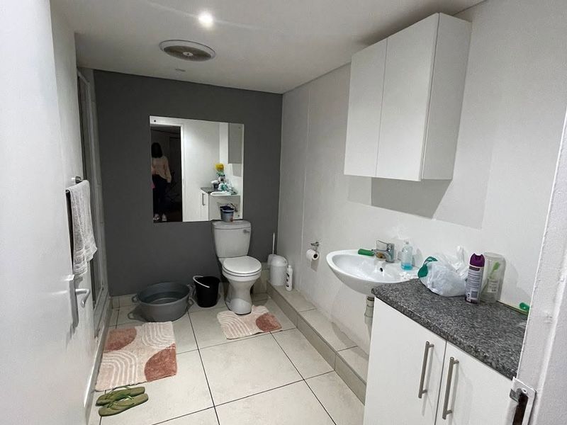 A functional bathroom featuring a vanity cabinet with stone countertop, wall-mounted storage, toilet, and tiled flooring with recessed lighting.